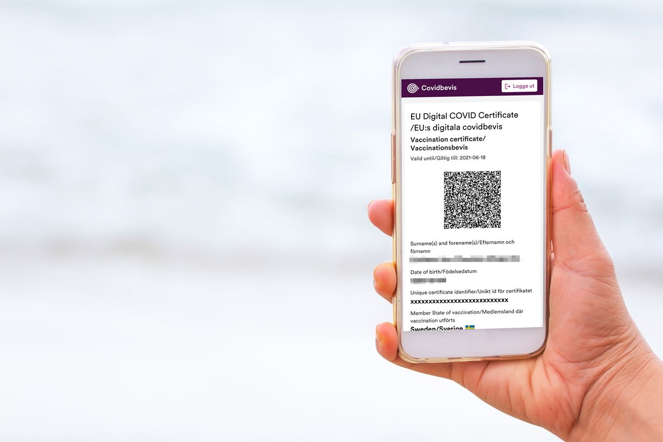 Hand som håller i en telefon som visar ett covidbevis 